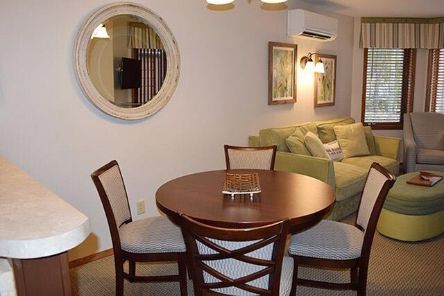 carpeted dining space featuring an AC wall unit