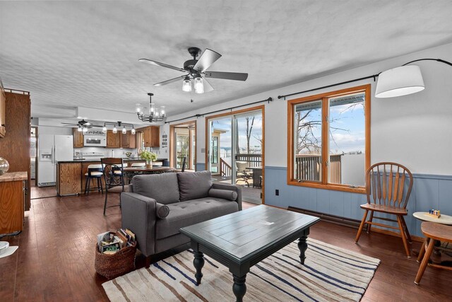1096 Lakeshore Dr, Menasha, WI 54952 - living area with ceiling fan with notable chandelier, a wainscoted wall, a textured ceiling, and dark wood-style flooring