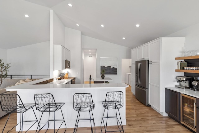 kitchen featuring white cabinets, appliances with stainless steel finishes, lofted ceiling, and wine cooler