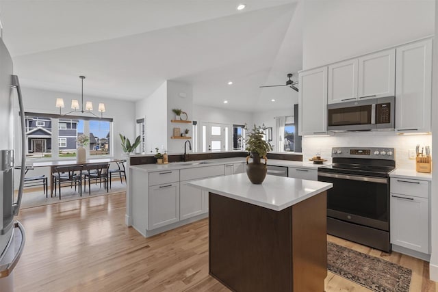 kitchen with a peninsula, light countertops, a sink, light wood-style flooring, and stainless steel appliances