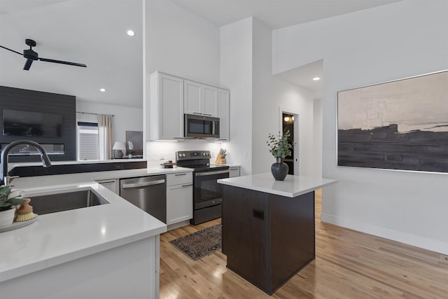 kitchen featuring light countertops, white cabinets, a sink, light wood finished floors, and stainless steel appliances