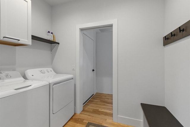 washroom featuring cabinet space, light wood-style flooring, and independent washer and dryer