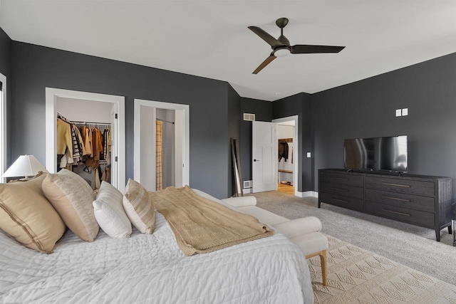 bedroom featuring a walk in closet, visible vents, light colored carpet, baseboards, and a closet