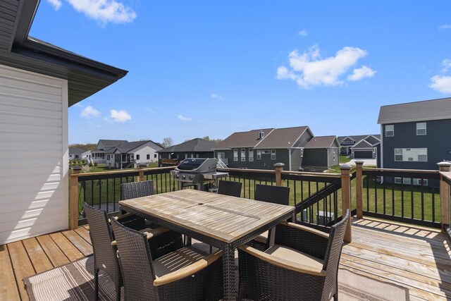deck featuring a lawn, grilling area, a residential view, and outdoor dining space