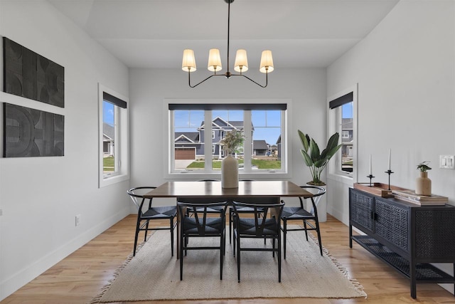 dining area featuring baseboards, light wood-type flooring, and a chandelier