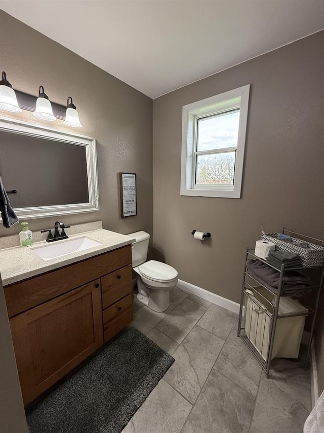 bathroom featuring baseboards, marble finish floor, vanity, and toilet