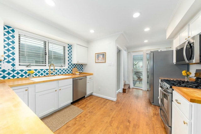kitchen featuring a sink, decorative backsplash, stainless steel appliances, butcher block counters, and white cabinets