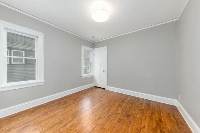 empty room with baseboards, ornamental molding, and hardwood / wood-style floors