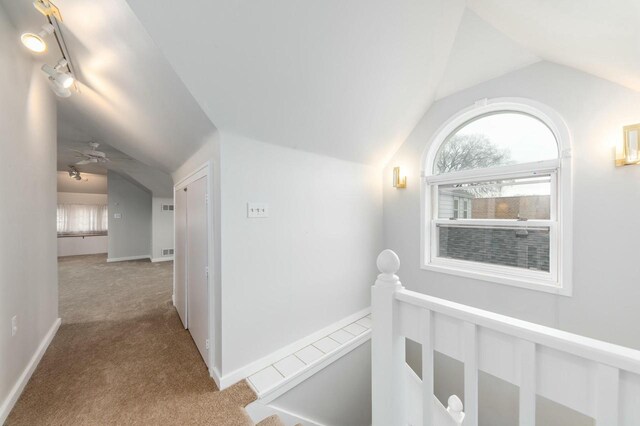 hall featuring vaulted ceiling, an upstairs landing, carpet floors, and baseboards