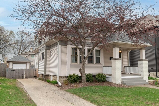 view of front of property featuring a gate, fence, concrete driveway, covered porch, and a detached garage