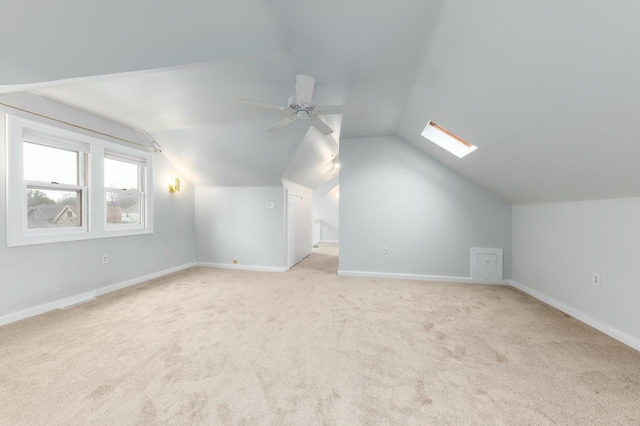 additional living space with a ceiling fan, baseboards, carpet, and vaulted ceiling with skylight