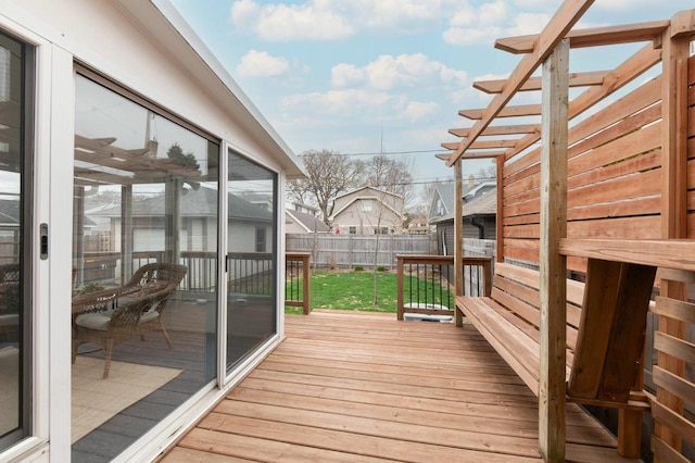wooden deck featuring a sunroom, a fenced backyard, and a lawn