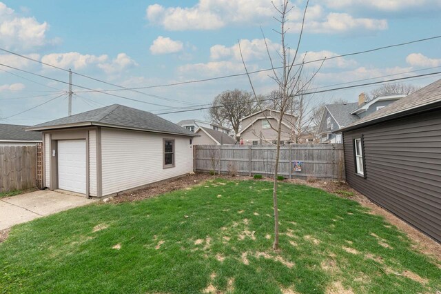 view of yard featuring a detached garage, driveway, an outbuilding, and a fenced backyard