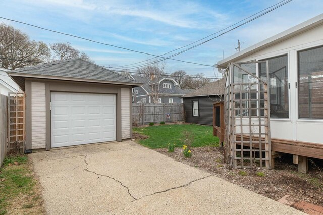 view of yard with fence, concrete driveway, an outdoor structure, a sunroom, and a garage