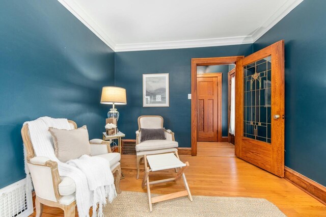 sitting room with visible vents, baseboards, wood finished floors, and ornamental molding