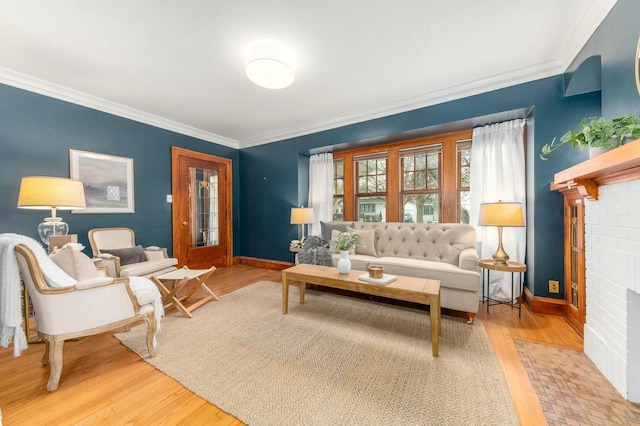living area with a fireplace, wood finished floors, baseboards, and ornamental molding