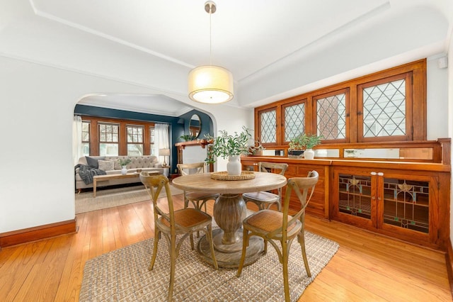 dining room featuring baseboards, arched walkways, and light wood-style floors