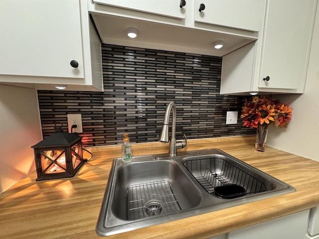 4 Hawthorn Trl, Wisconsin Dells, WI 53965 - room details featuring a sink, backsplash, and white cabinetry