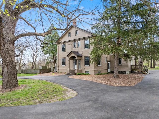 28094 E State Rd, Island Lake, IL 60042 - view of front facade featuring a chimney, fence, driveway, and stucco siding