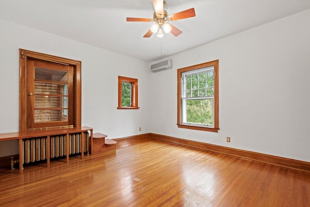 28094 E State Rd, Island Lake, IL 60042 - unfurnished room with radiator heating unit, a wall mounted air conditioner, wood finished floors, a ceiling fan, and baseboards