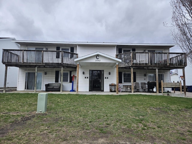 back of house with a lawn, a wooden deck, and a patio area