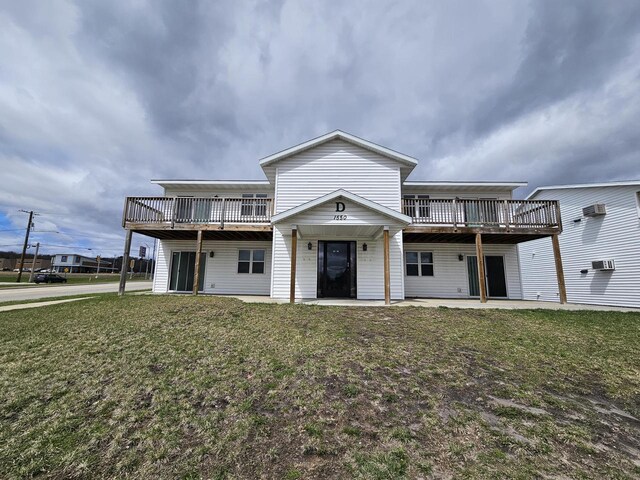 rear view of property featuring a wooden deck, a yard, and a wall unit AC