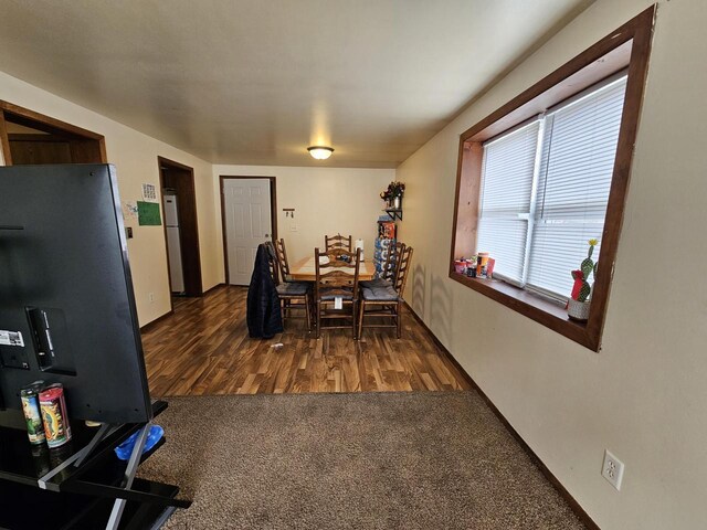 dining room with dark colored carpet, baseboards, and dark wood-type flooring