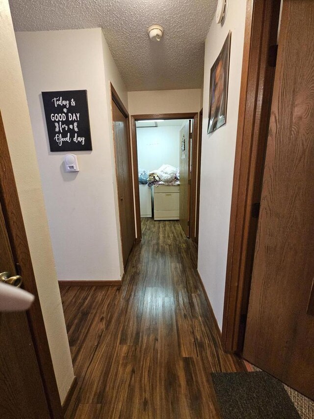 corridor featuring dark wood finished floors, baseboards, and a textured ceiling