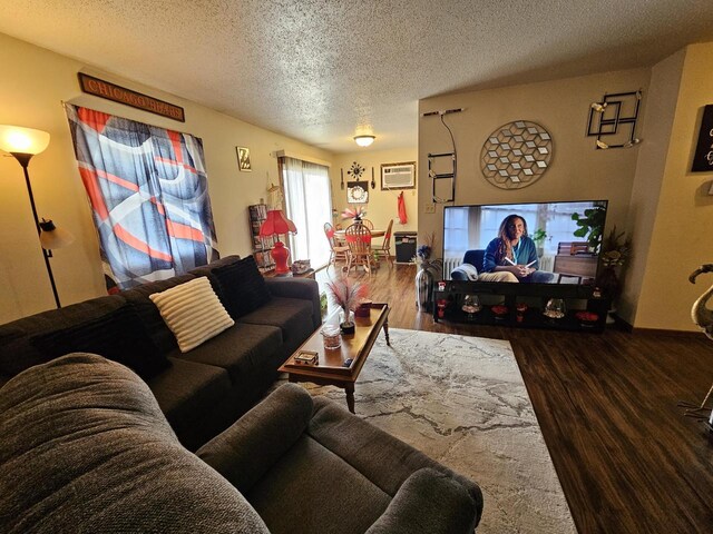 living room featuring wood finished floors, a textured ceiling, and a wall unit AC