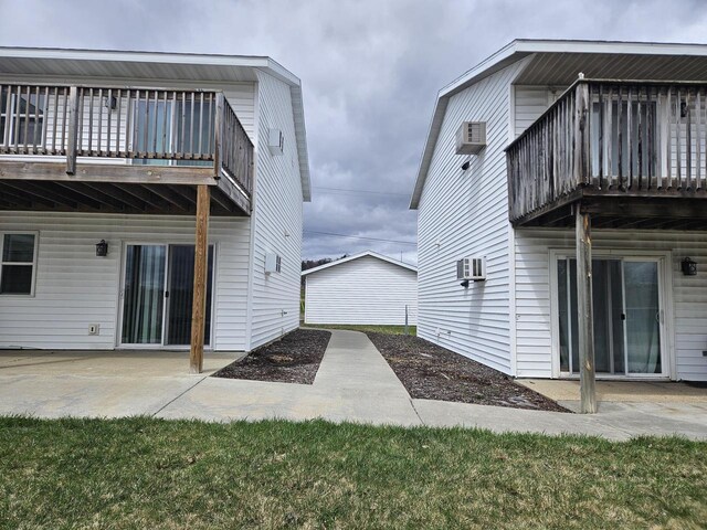 back of house with a wall mounted AC, a patio, and a balcony