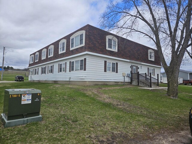 exterior space with a shingled roof, a front yard, and mansard roof