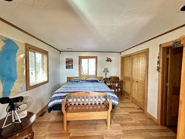 bedroom featuring ornamental molding, a textured ceiling, and light wood-style flooring