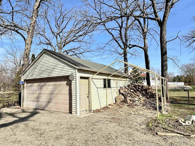 view of side of property with an outdoor structure, a detached garage, and fence