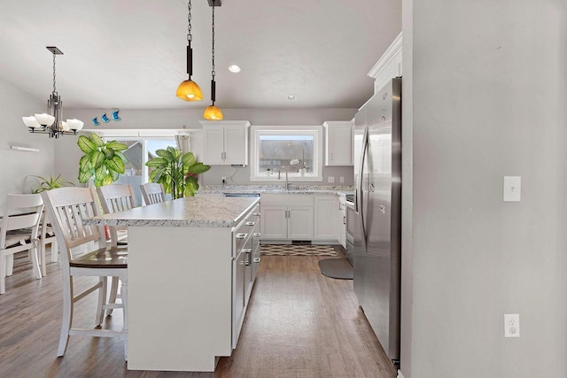 830 Roth Rd, De Pere, WI 54115 - kitchen featuring a center island, wood finished floors, white cabinetry, and stainless steel fridge