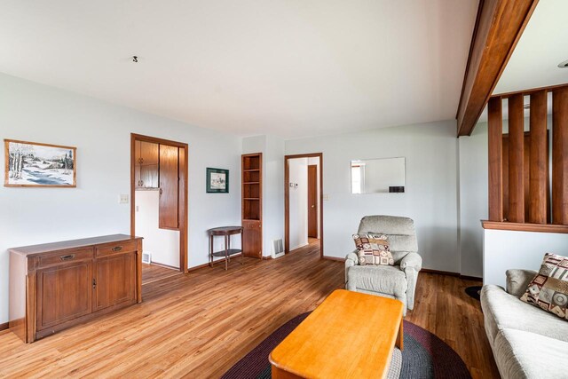 living room with baseboards, visible vents, and light wood-style flooring