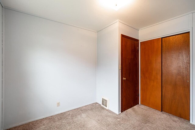 unfurnished bedroom featuring a closet, carpet, and visible vents