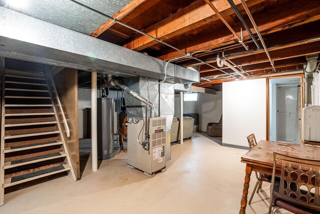 unfinished below grade area featuring water heater, stairway, and heating unit