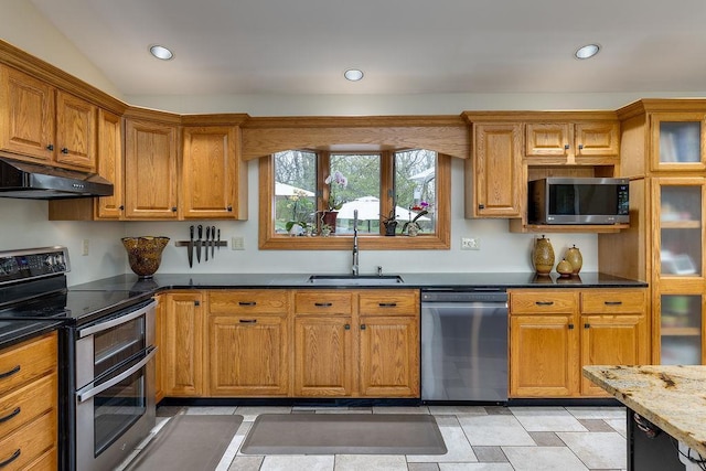 kitchen with appliances with stainless steel finishes, a sink, brown cabinetry, recessed lighting, and under cabinet range hood