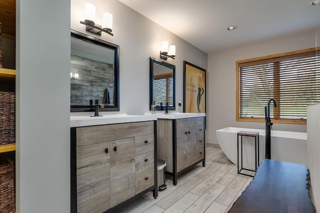 full bathroom featuring a freestanding tub, vanity, recessed lighting, and wood finished floors