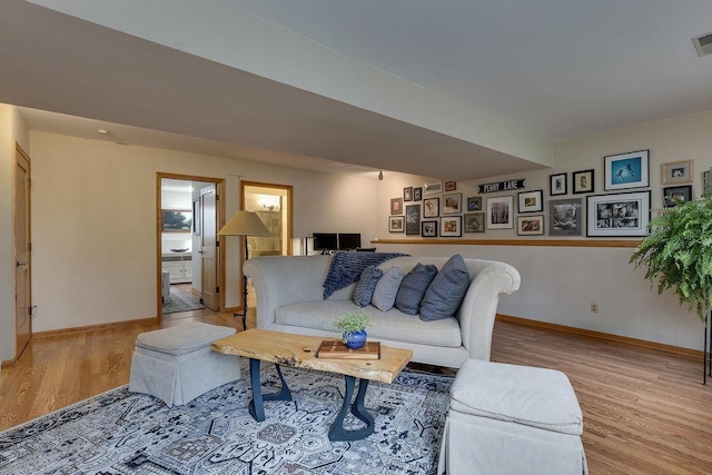 living room with baseboards, visible vents, and light wood-style floors