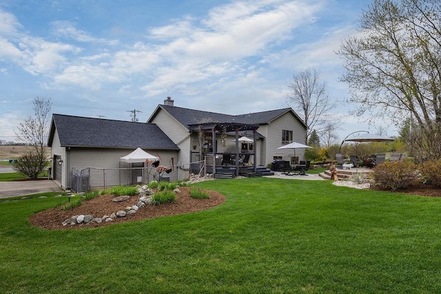 back of property with a yard, fence, a chimney, and a shingled roof