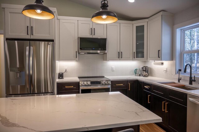 W3090 Yellow Banks Trl, Nekoosa, WI 54457 - kitchen with light stone counters, a sink, decorative backsplash, glass insert cabinets, and appliances with stainless steel finishes