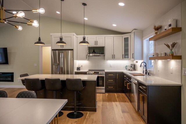 W3090 Yellow Banks Trl, Nekoosa, WI 54457 - kitchen featuring a kitchen breakfast bar, stainless steel appliances, open shelves, vaulted ceiling, and a sink