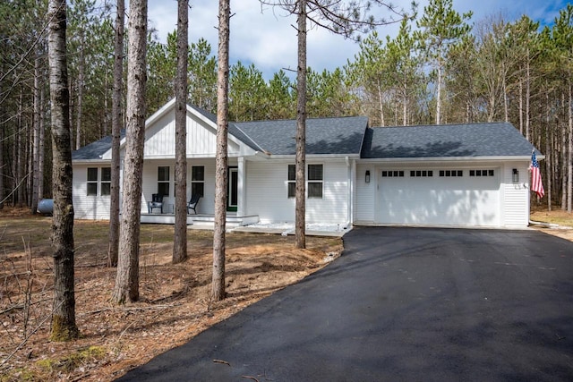 W3090 Yellow Banks Trl, Nekoosa, WI 54457 - view of front of home featuring aphalt driveway, roof with shingles, covered porch, and a garage