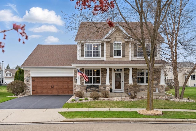 craftsman-style home with roof with shingles, an attached garage, stone siding, a porch, and driveway