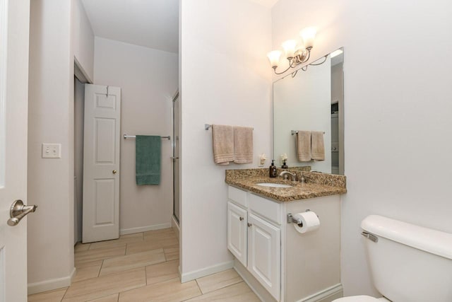 1300 N Prospect Ave Unit 120, Milwaukee, WI 53202 - full bathroom featuring a shower with shower door, an inviting chandelier, toilet, vanity, and baseboards