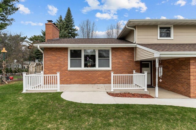 1442 Traeger St, Green Bay, WI 54304 - view of front of home with a chimney, a front lawn, roof with shingles, a patio, and brick siding