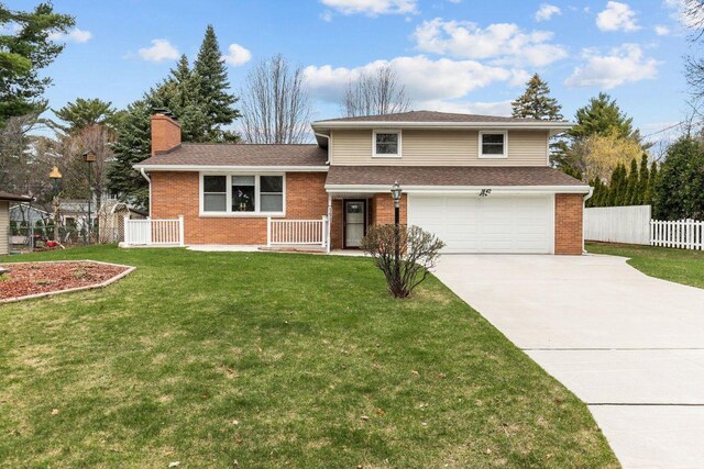 1442 Traeger St, Green Bay, WI 54304 - tri-level home featuring a chimney, concrete driveway, fence, brick siding, and an attached garage