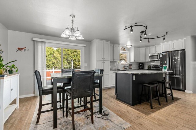 1442 Traeger St, Green Bay, WI 54304 - kitchen featuring white cabinets, a kitchen island, a notable chandelier, and appliances with stainless steel finishes