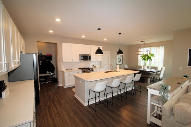 1677 Liatris Dr, Sun Prairie, WI 53590 - kitchen with dark wood-style floors, a kitchen bar, tasteful backsplash, a sink, and appliances with stainless steel finishes
